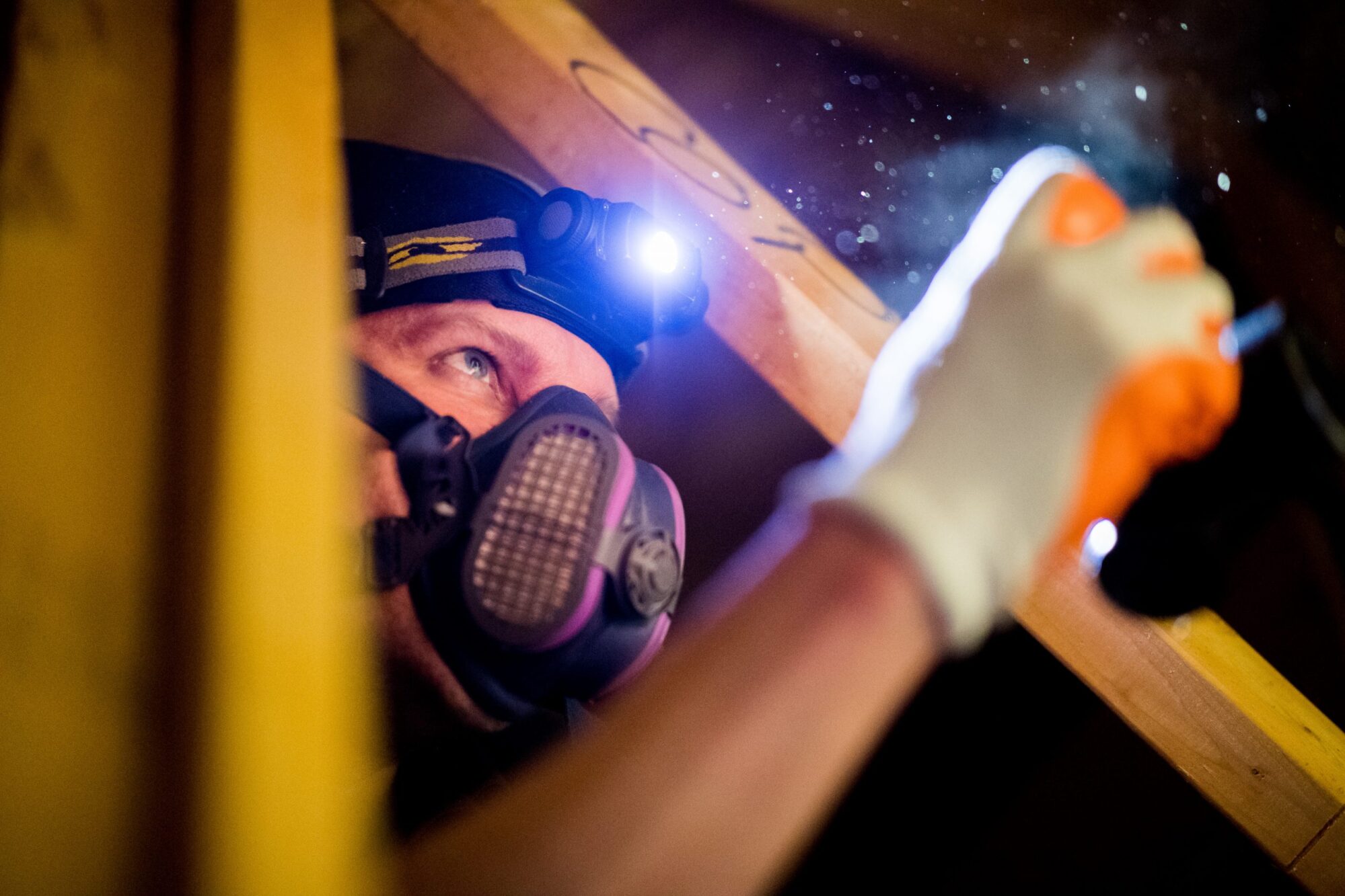 Phillip McClain inspecting attic with headlamp
